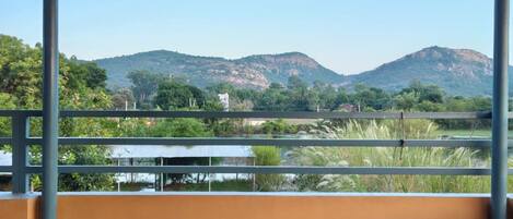 A balcony with a view of mountains and greenery.