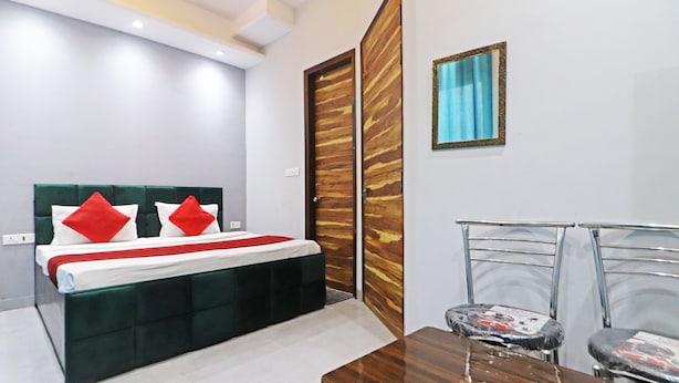 A modern bedroom with a bed, a wooden door, a framed picture, and a dining table with chairs. - Twamev Rajouri garden by The Arrow (New Delhi)