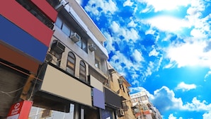 A street view with buildings, some with storefronts and signage, under a partly cloudy sky. - Twamev Rajouri garden by The Arrow (New Delhi)