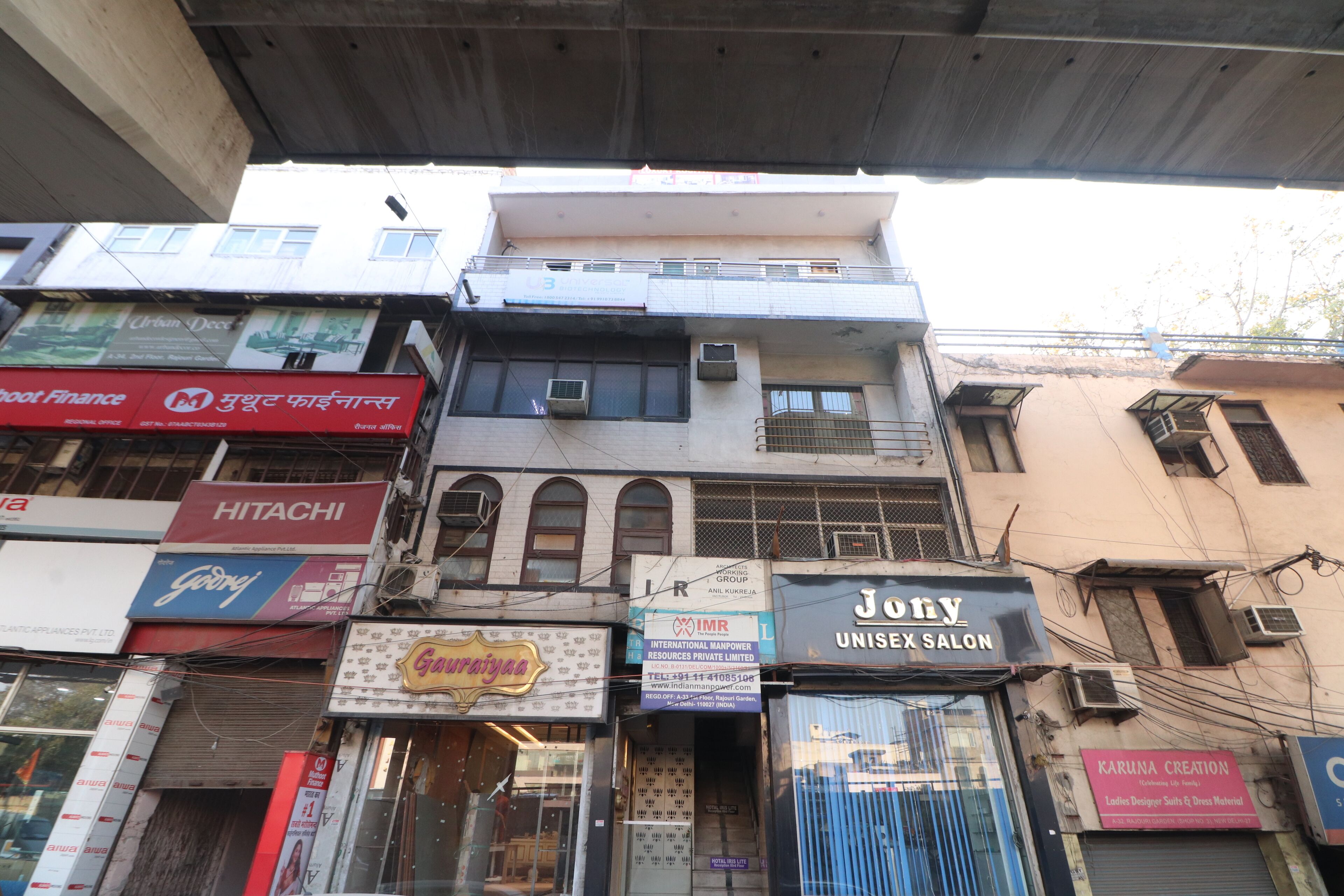 A multi-story building with various commercial establishments on the ground floor, including a salon and a design studio.