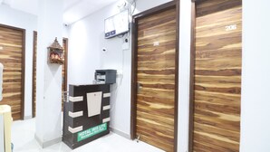 A reception area with a reception desk labeled "HOTEL IRIS LITE" and a sign indicating "Reception on 1st floor." There are two wooden doors with numbers 205 and 206. - Twamev Rajouri garden by The Arrow (New Delhi)