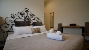 Una cama bien hecha con un edredón estampado, un cabecero con diseño decorativo y un espejo en la pared.