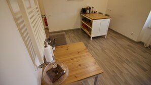 Una habitación pequeña con una mesa de madera, un armario blanco y un radiador.