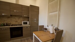 Una cocina moderna con armarios de madera, un microondas y una mesa de comedor con una silla.