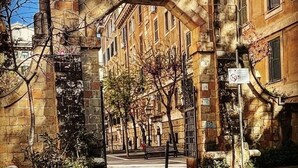 Un arco de piedra con un ventanal circular, que da a una calle bordeada de edificios.