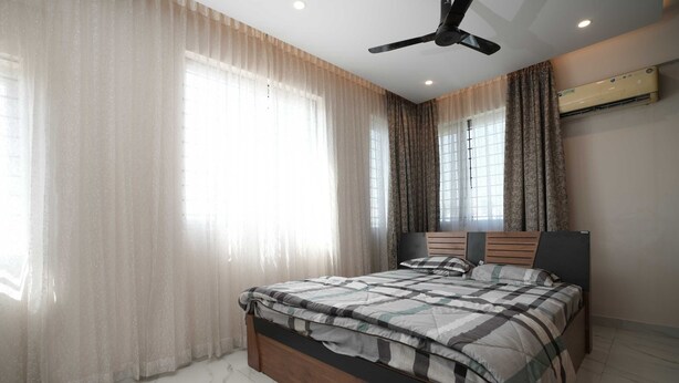 A bedroom with a bed, curtains, a ceiling fan, and an air conditioning unit. - Srushti Service Apartment (Bengaluru)