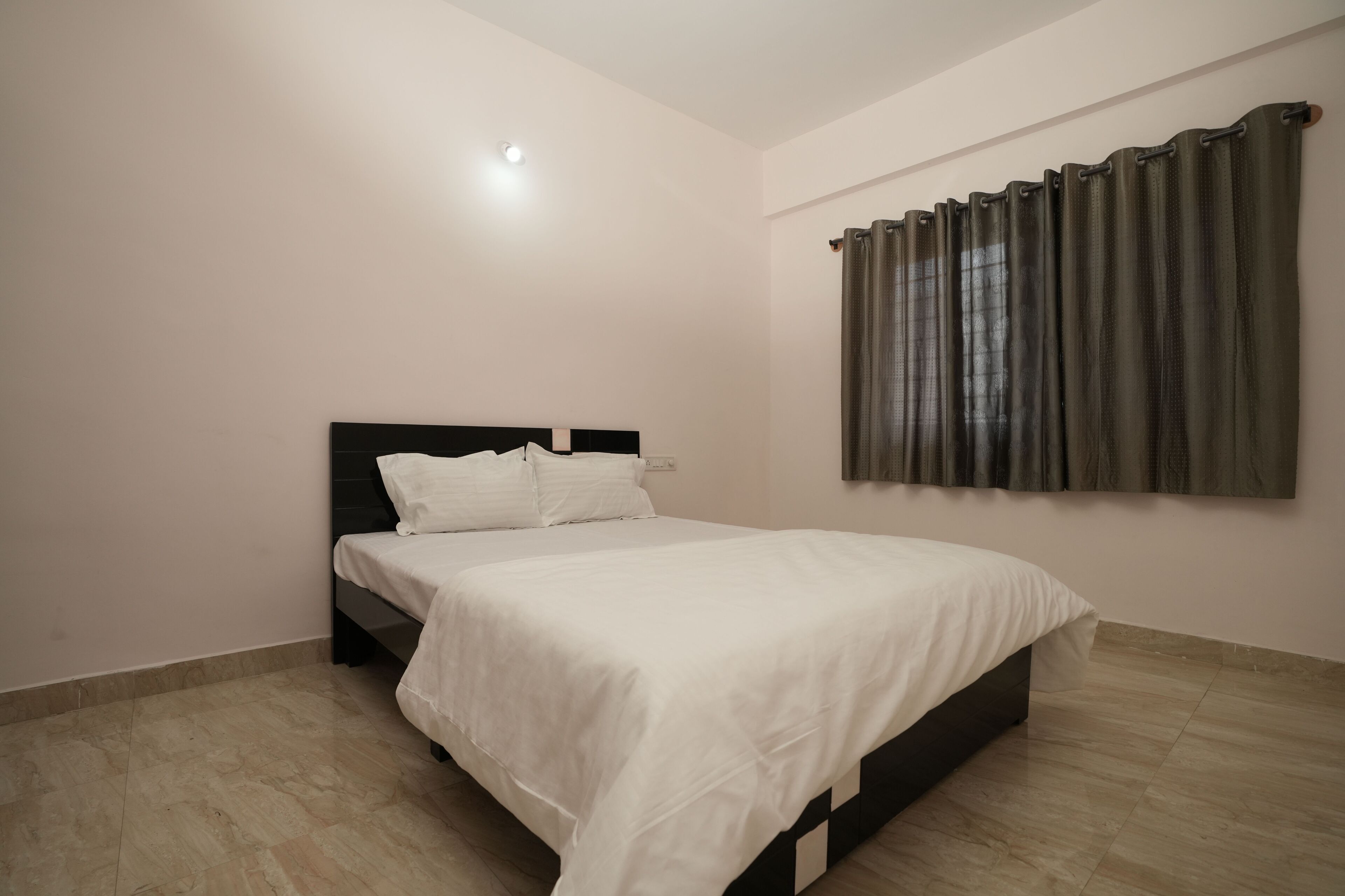 A bedroom with a bed, a headboard, and a window with curtains.