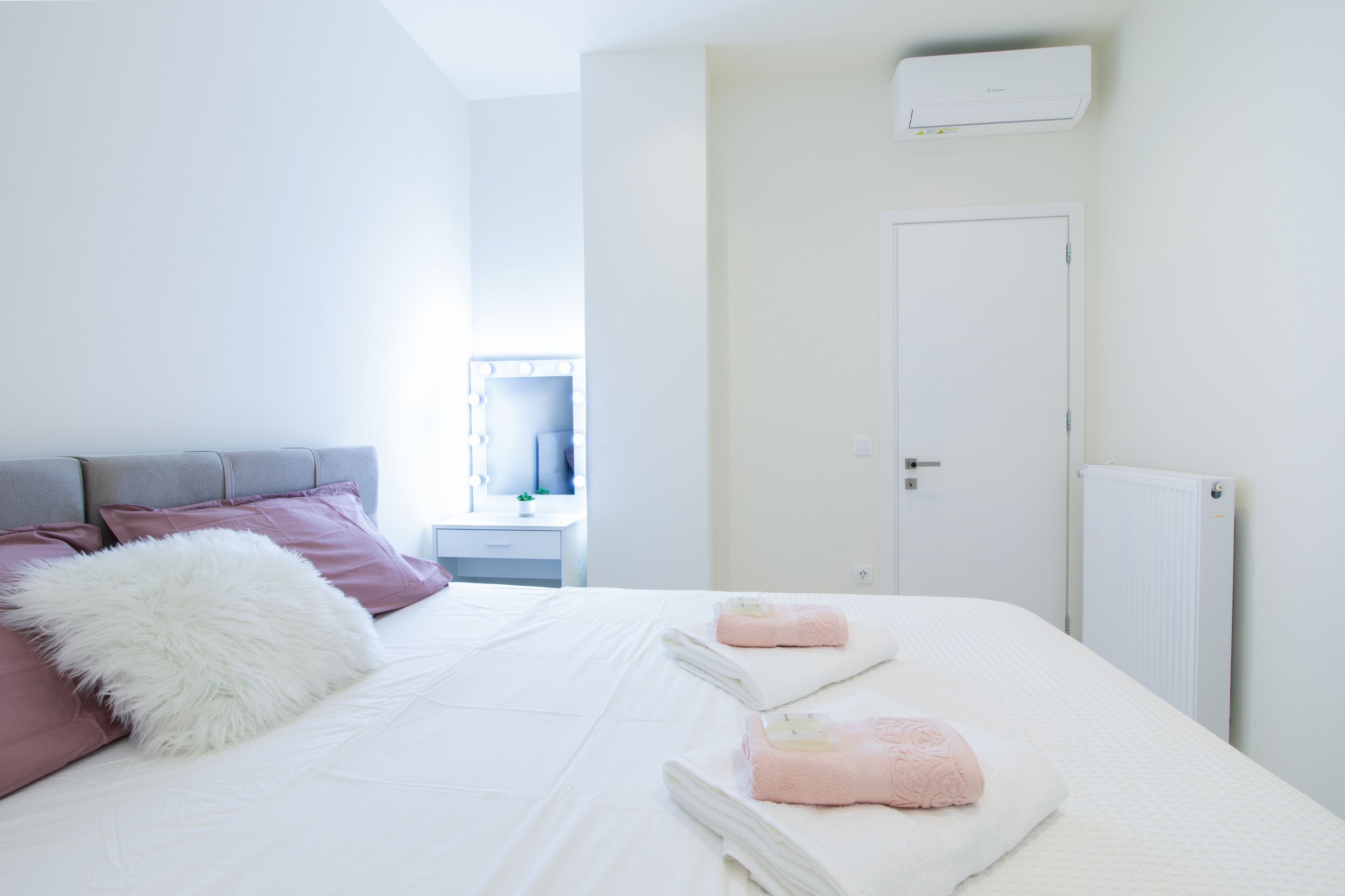 Una camera da letto con un letto, cuscini, un comodino, uno specchio e un termosifone.