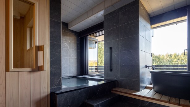 A modern bathroom with a freestanding bathtub, a wooden vanity, and a large window providing a view of the outdoors. - Sengokubara cocon (Hakone)
