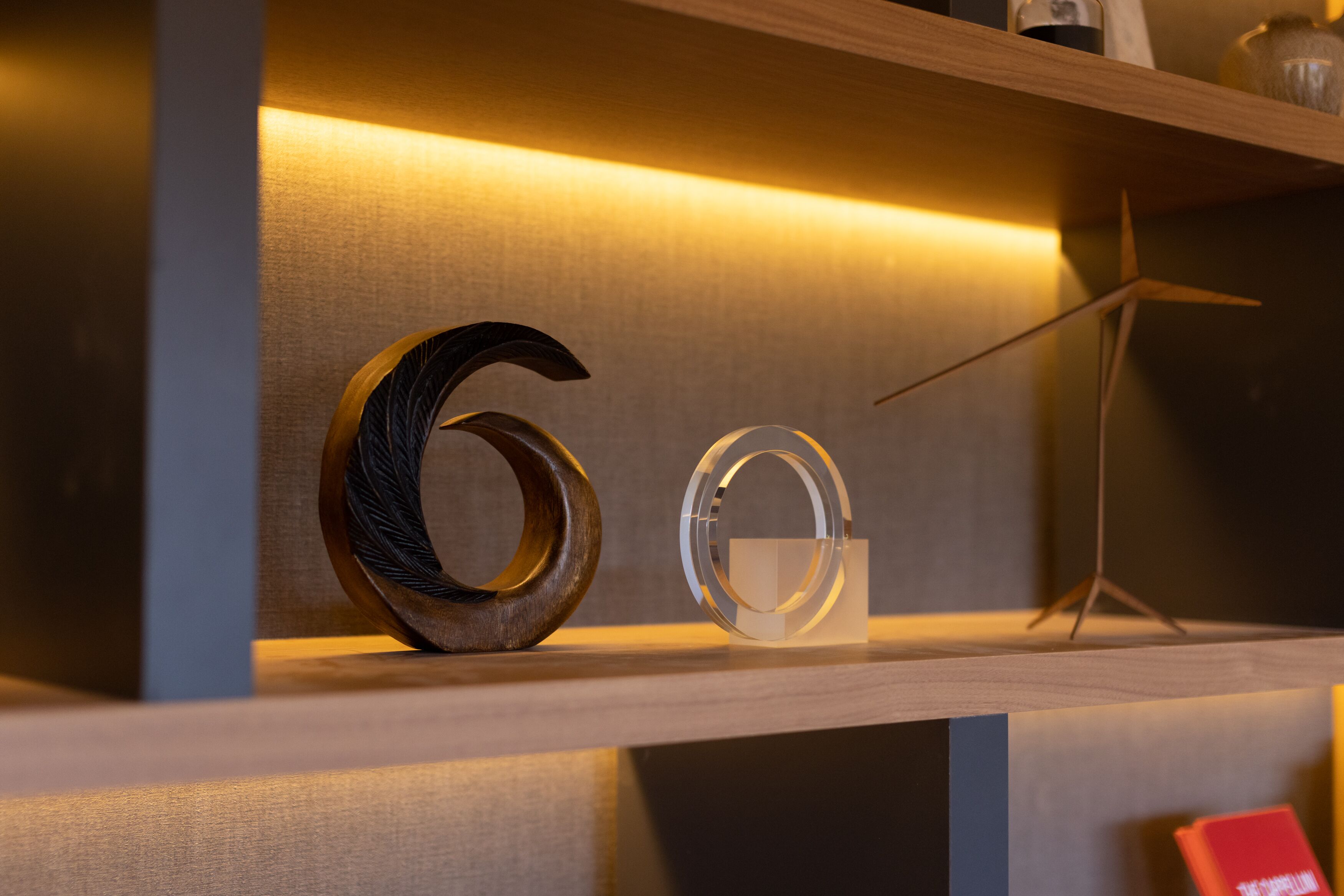 Una estantería con el número '6' de madera y un objeto circular transparente.