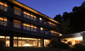 Un edificio moderno con varios balcones, grandes ventanales y una zona de entrada bien iluminada.