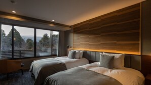 A modern hotel room with two beds, a large window with a view of trees and mountains, and a wooden headboard. - Sengokubara cocon (Hakone)