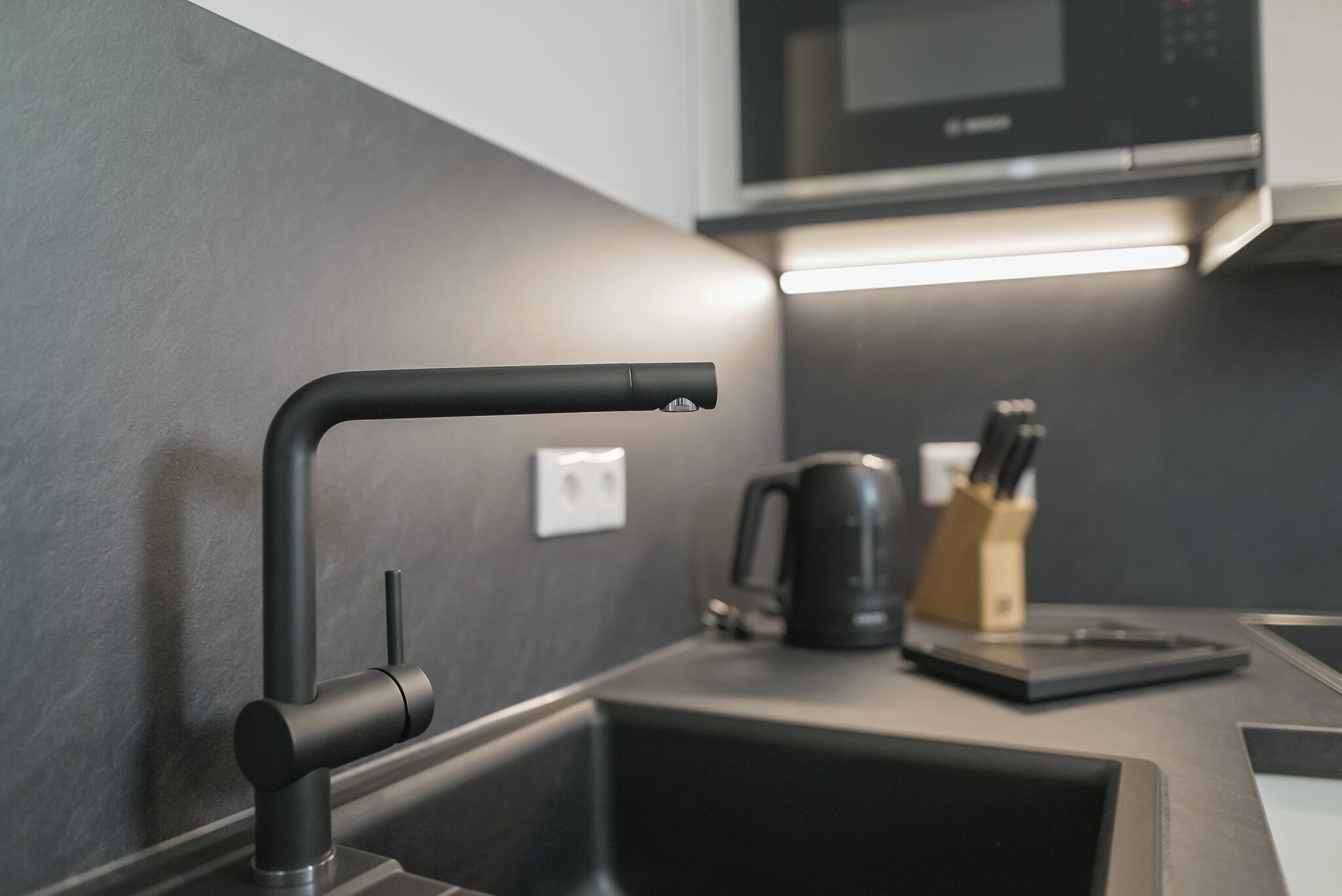 A modern kitchen with a sleek black faucet, a coffee maker, and a microwave on the countertop.