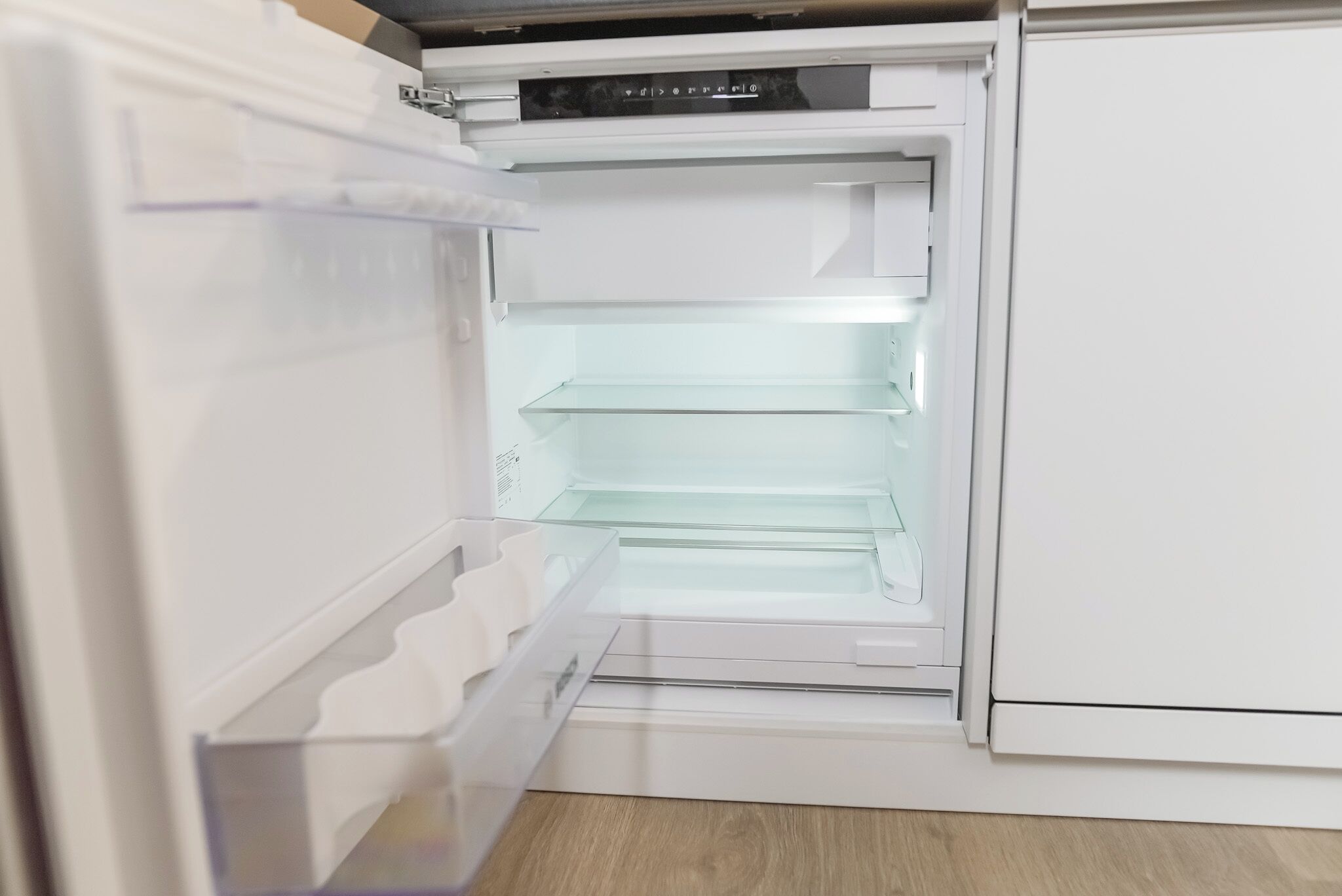 Un réfrigérateur ouvert, avec des étagères transparentes et un panneau de commande.