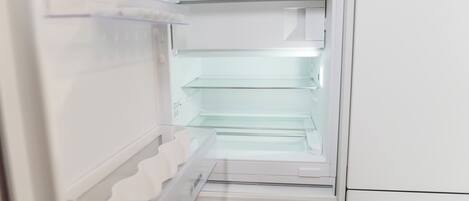 An open refrigerator with clear shelves and a control panel.