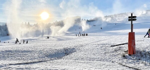 Une piste de ski enneigée, avec un télésiège et un panneau indicateur.