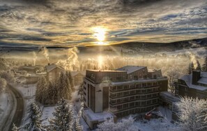 A snow-covered building complex with multiple structures, including a large central building with a sign that reads "Austritt in Historisches Ambergerland." - Summit of Saxony Resort Oberwiesenthal (Oberwiesenthal)