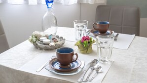 Une table dressée avec une tasse marron, un verre transparent, une bouteille et un petit vase avec des fleurs.