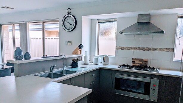 Een moderne keuken met een centraal eiland, een ingebouwde oven, gasfornuis en een groot raam voor natuurlijk licht.