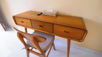 Un escritorio de madera con una caja de pañuelos trenzada y un control remoto encima.