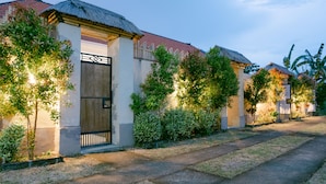 Un edificio residencial con techo de paja, puerta de madera y un jardín bien cuidado.