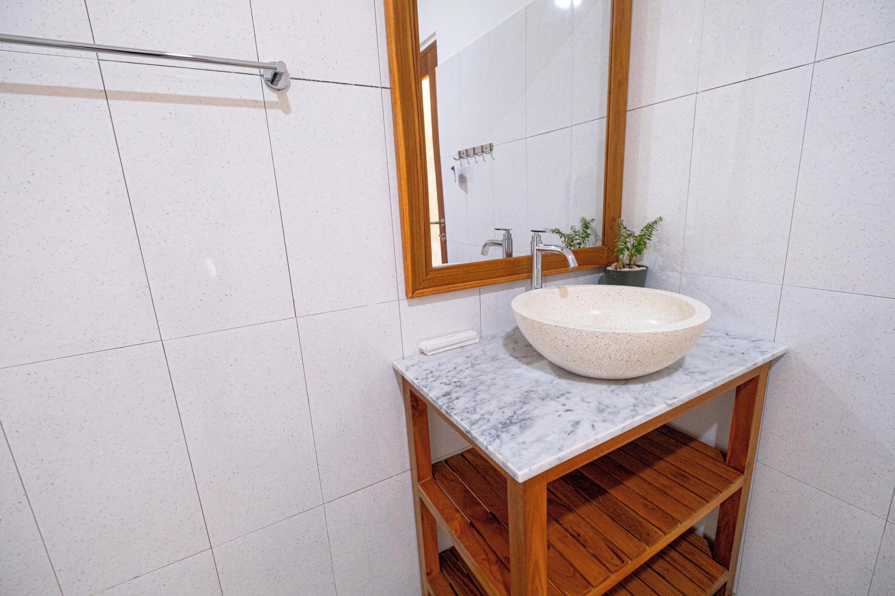 A bathroom with a marble sink, wooden vanity, and a mirror with a wooden frame.