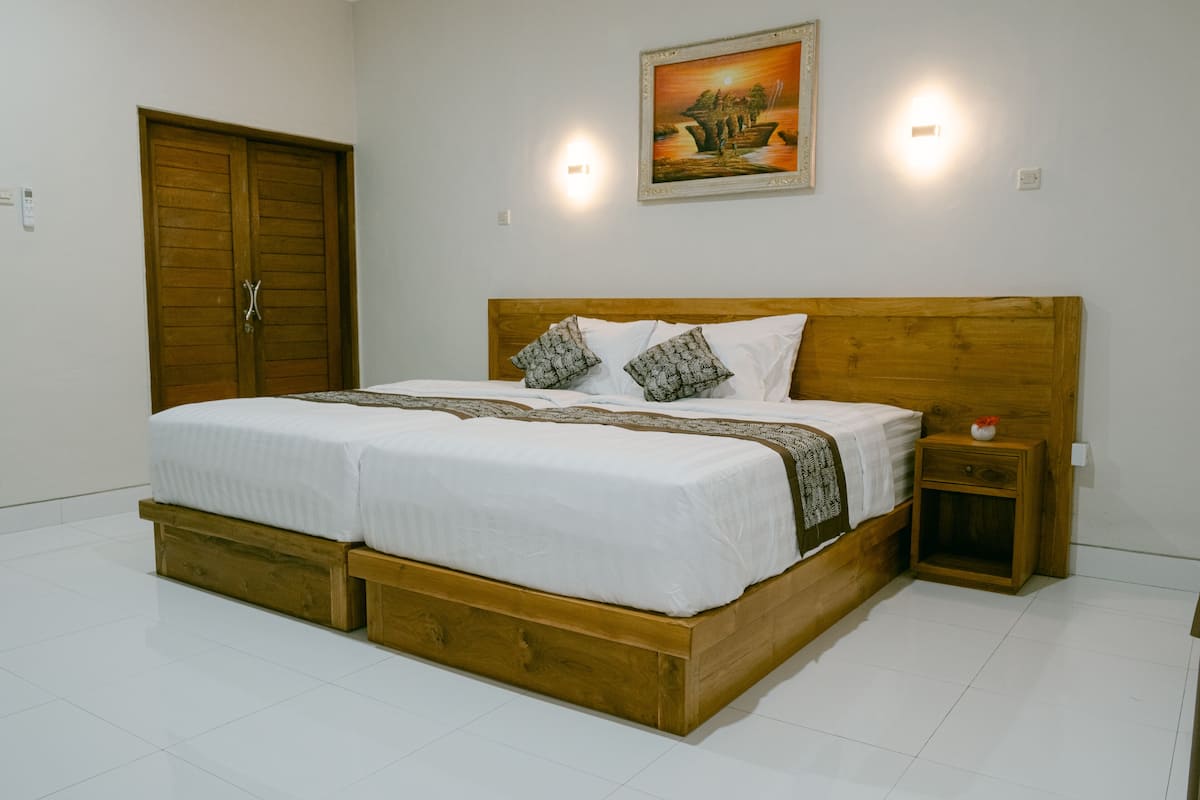 Un dormitorio con una cama de madera, ropa de cama blanca, dos mesitas de noche y un cuadro en la pared.