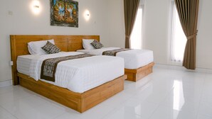 Habitación de hotel con dos camas de madera, ropa de cama blanca, un cuadro en la pared y ventanas amplias con cortinas.