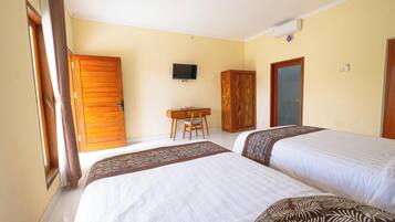 Una habitación de hotel con dos camas, un escritorio, un televisor y un armario.