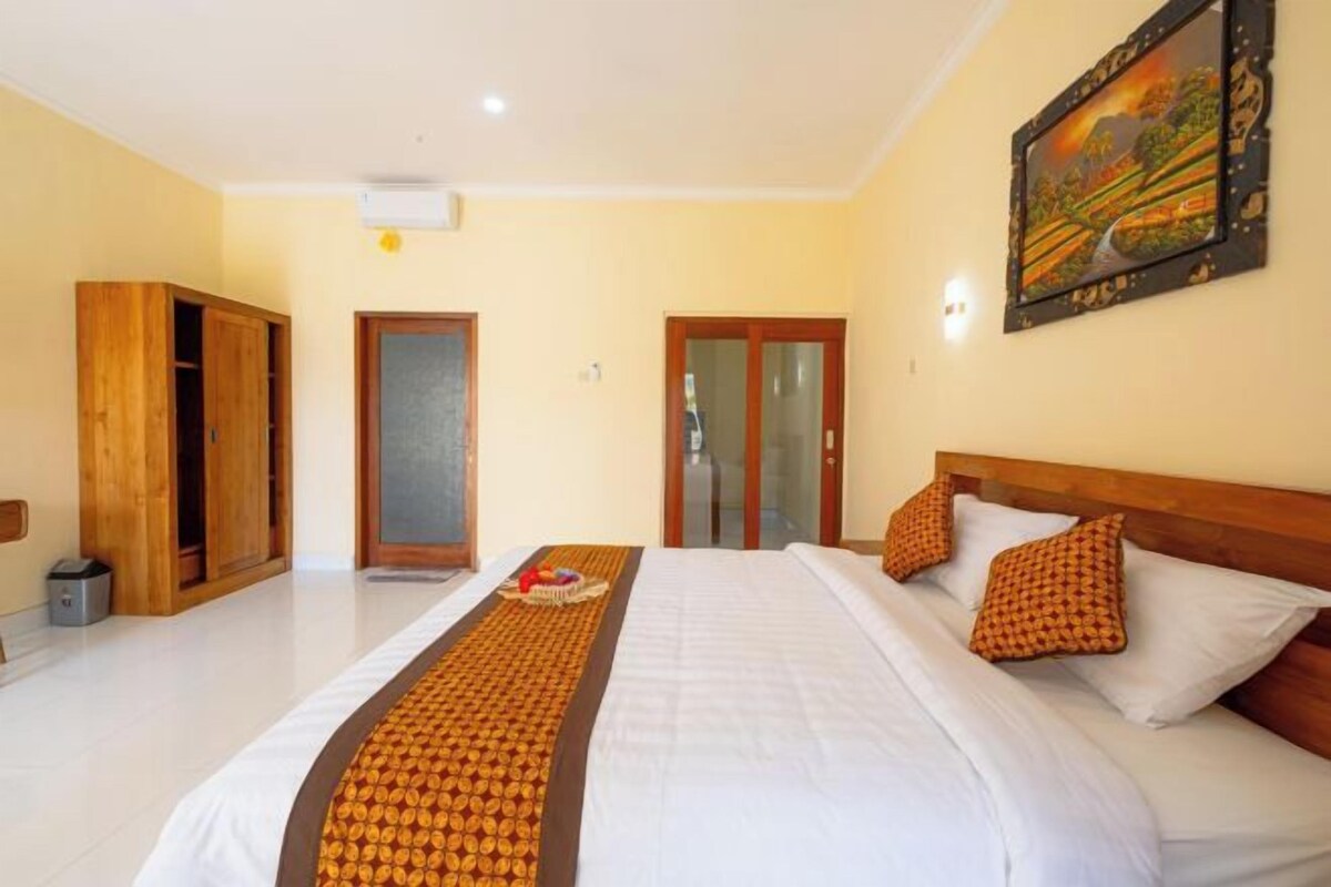 Una habitación de hotel con una cama grande, un armario de madera y un cuadro en la pared.