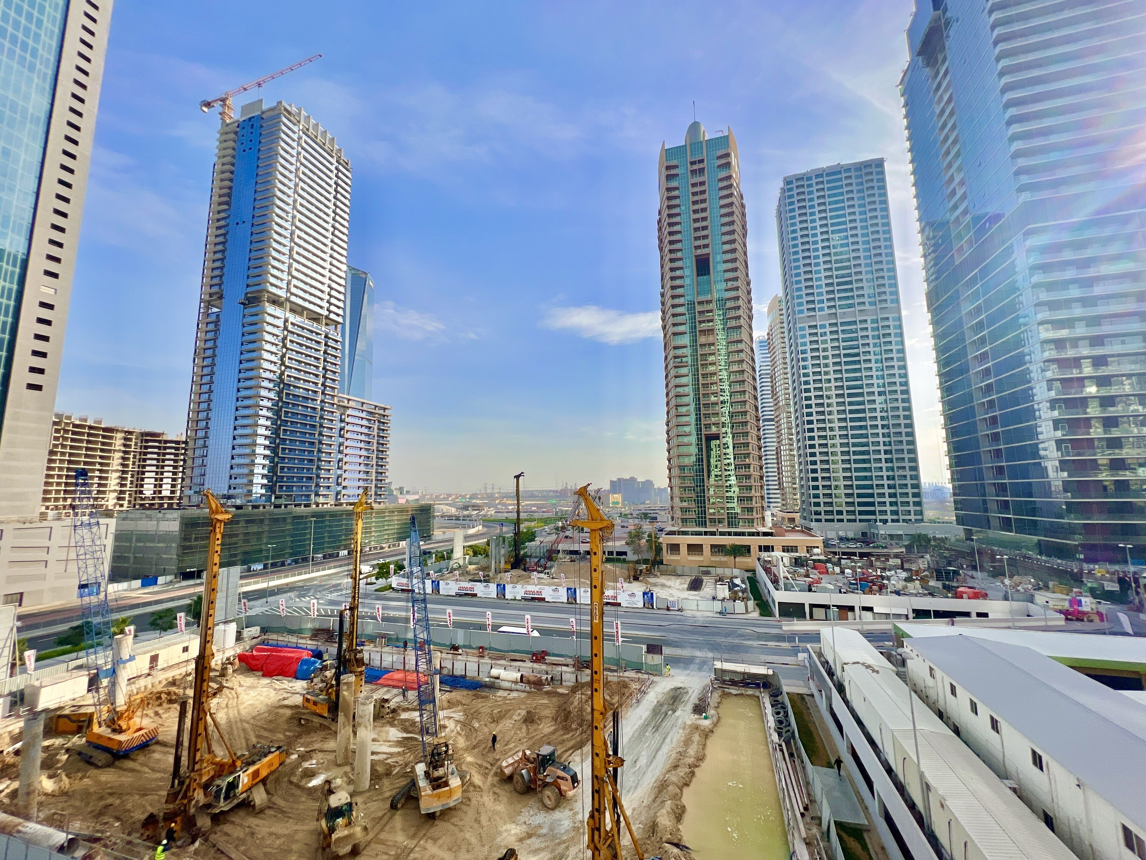 A construction site with multiple cranes and excavators, surrounded by high-rise buildings.