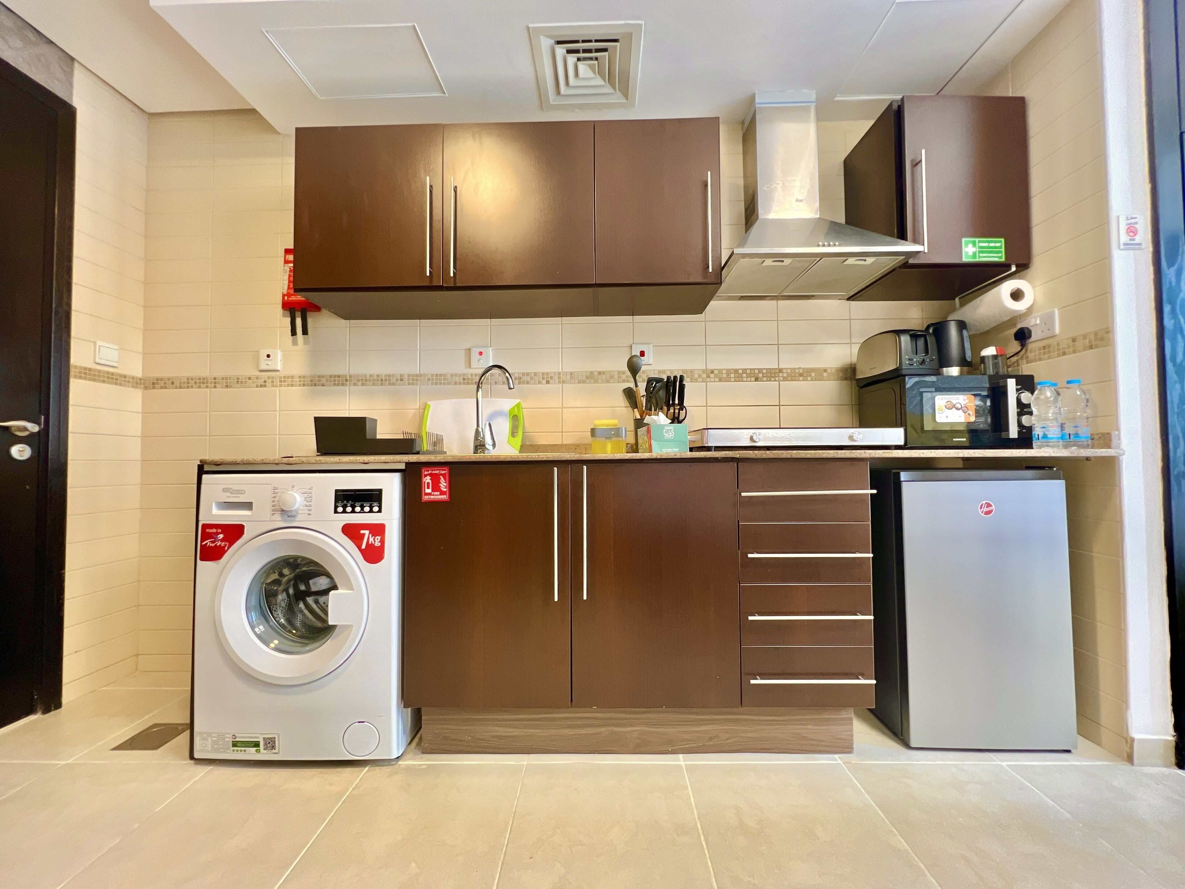 Eine kompakte Küche mit Waschmaschine, Kühlschrank und Mikrowelle.