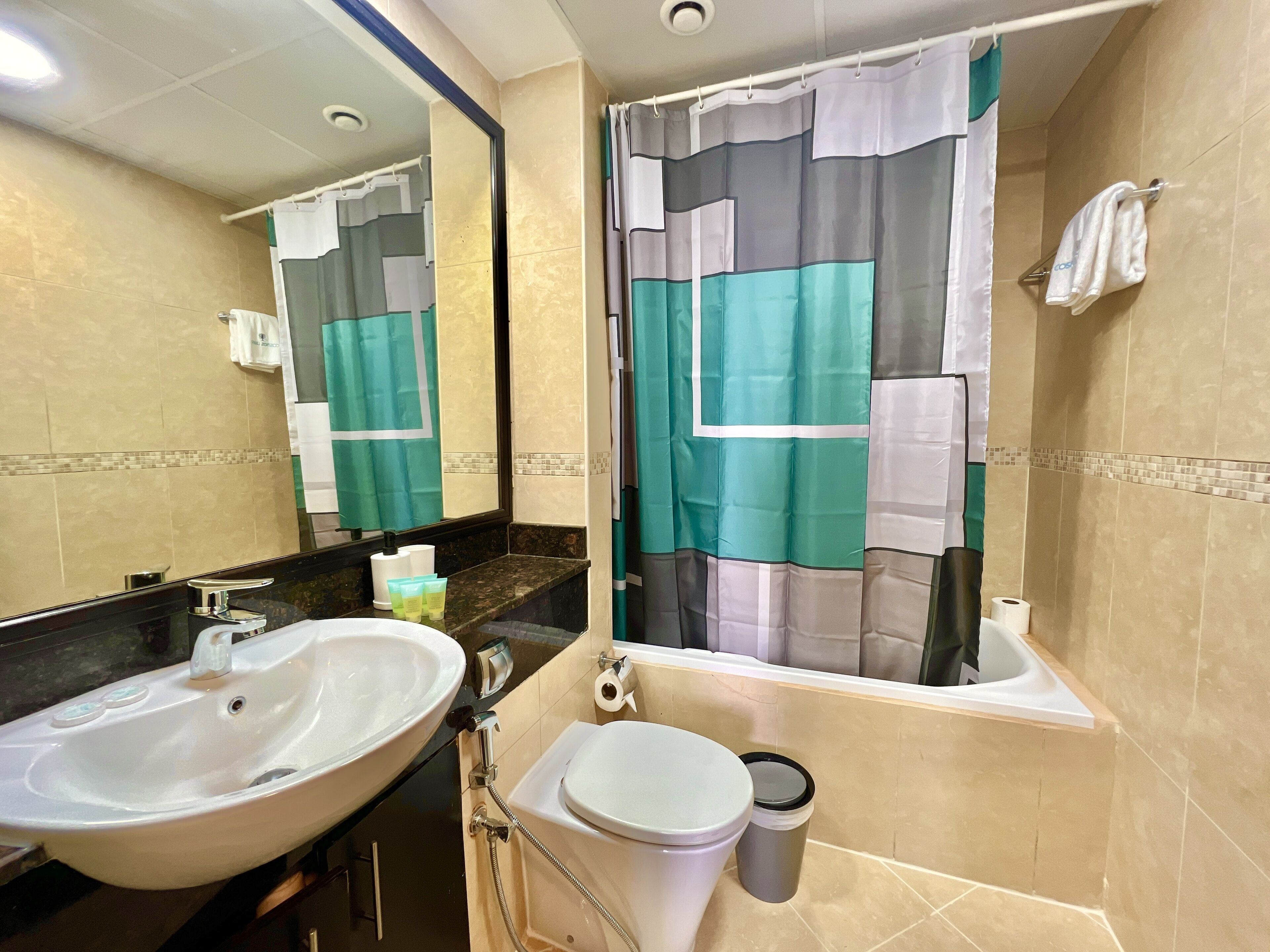 Un baño con lavamanos, inodoro y cortina de ducha.
