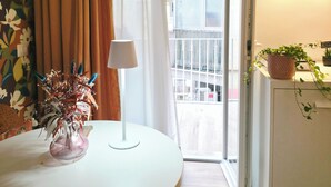 Une pièce avec une table ronde, une plante en pot, une lampe et une vue sur le balcon extérieur.