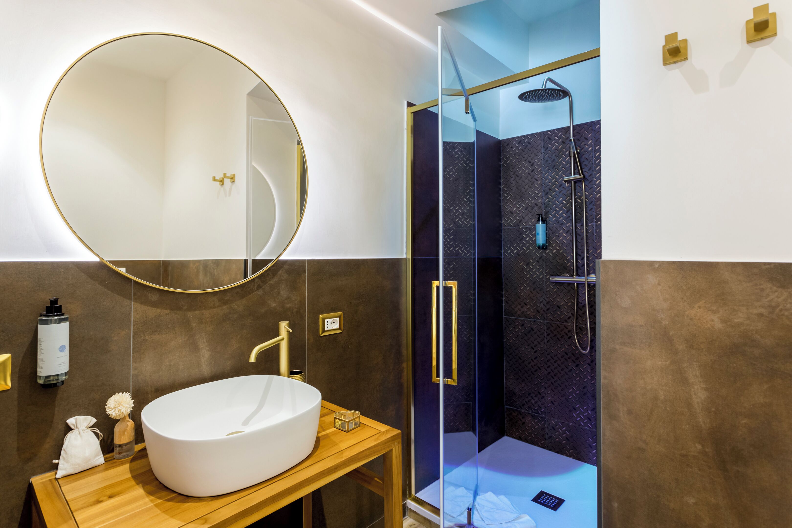 A modern bathroom with a large oval sink, a round mirror, and a glass-enclosed shower area.