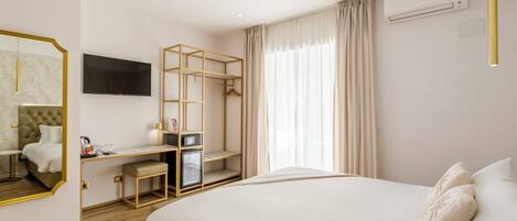 A modern hotel room with a large bed, a desk with a chair, a TV, and a wardrobe.