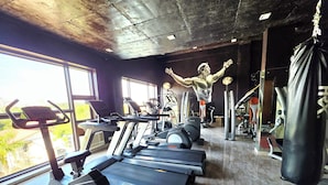 A gym with treadmills, stationary bikes, and a punching bag. - Chopra Farms and Resorts (Gurugram)
