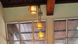 A wooden staircase leading to a room with large windows, a wooden ceiling, and hanging lamps. - Chopra Farms and Resorts (Gurugram)