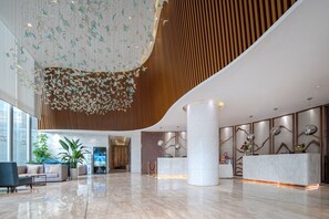 A spacious lobby with a reception desk, seating area, and decorative ceiling elements. - deluxe king (Shenzhen)
