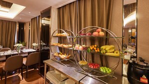 A hotel dining area with a buffet setup featuring various fruits and pastries. - deluxe king (Shenzhen)