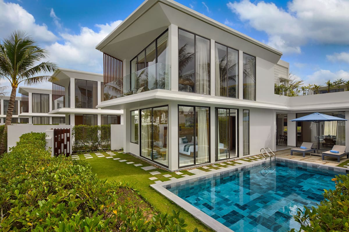 Una casa moderna de dos pisos con piscina, amplios ventanales y un jardín bien cuidado.