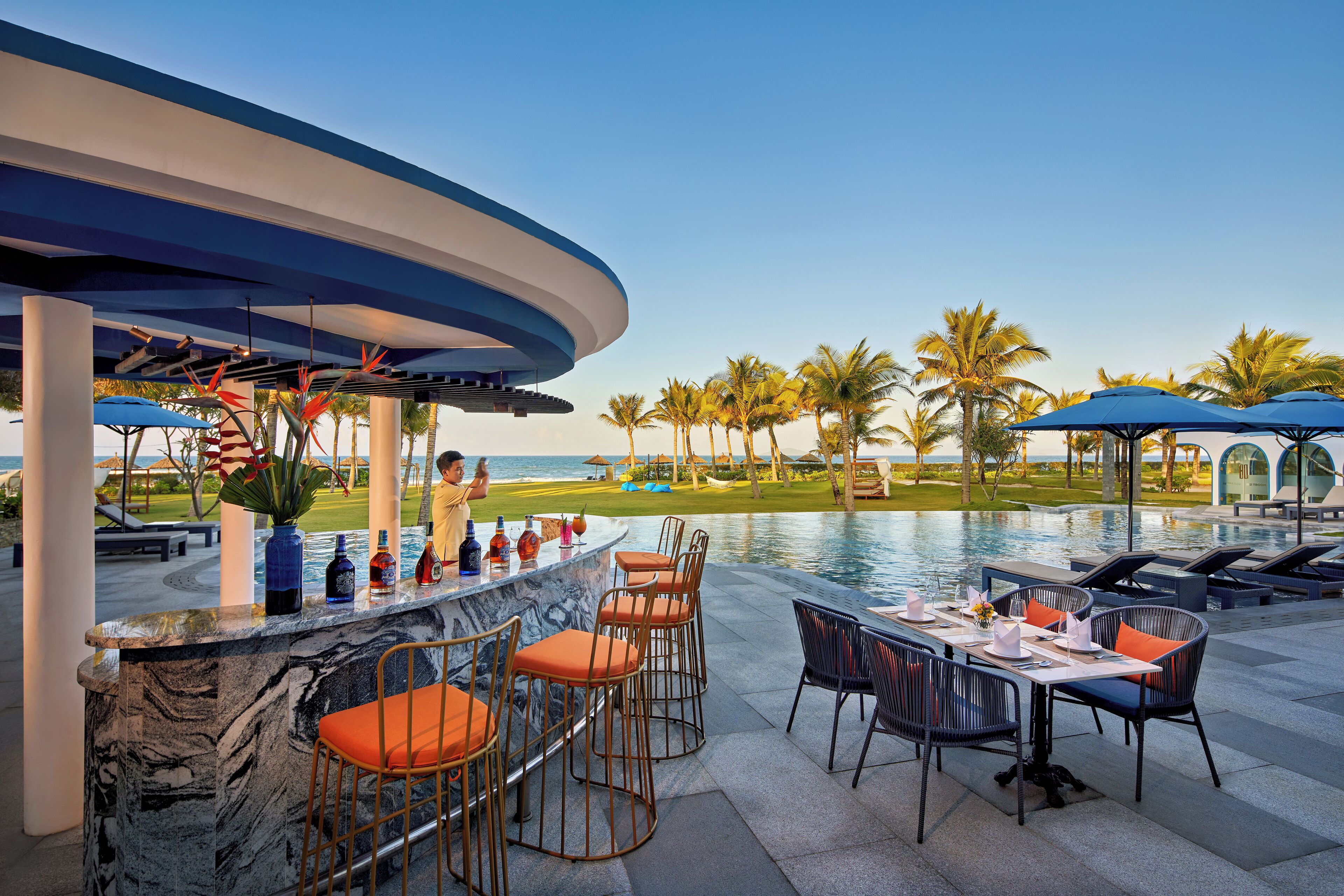 A poolside bar with seating and a view of the ocean.