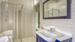 A modern bathroom with a glass shower enclosure, a white sink, and a large mirror.