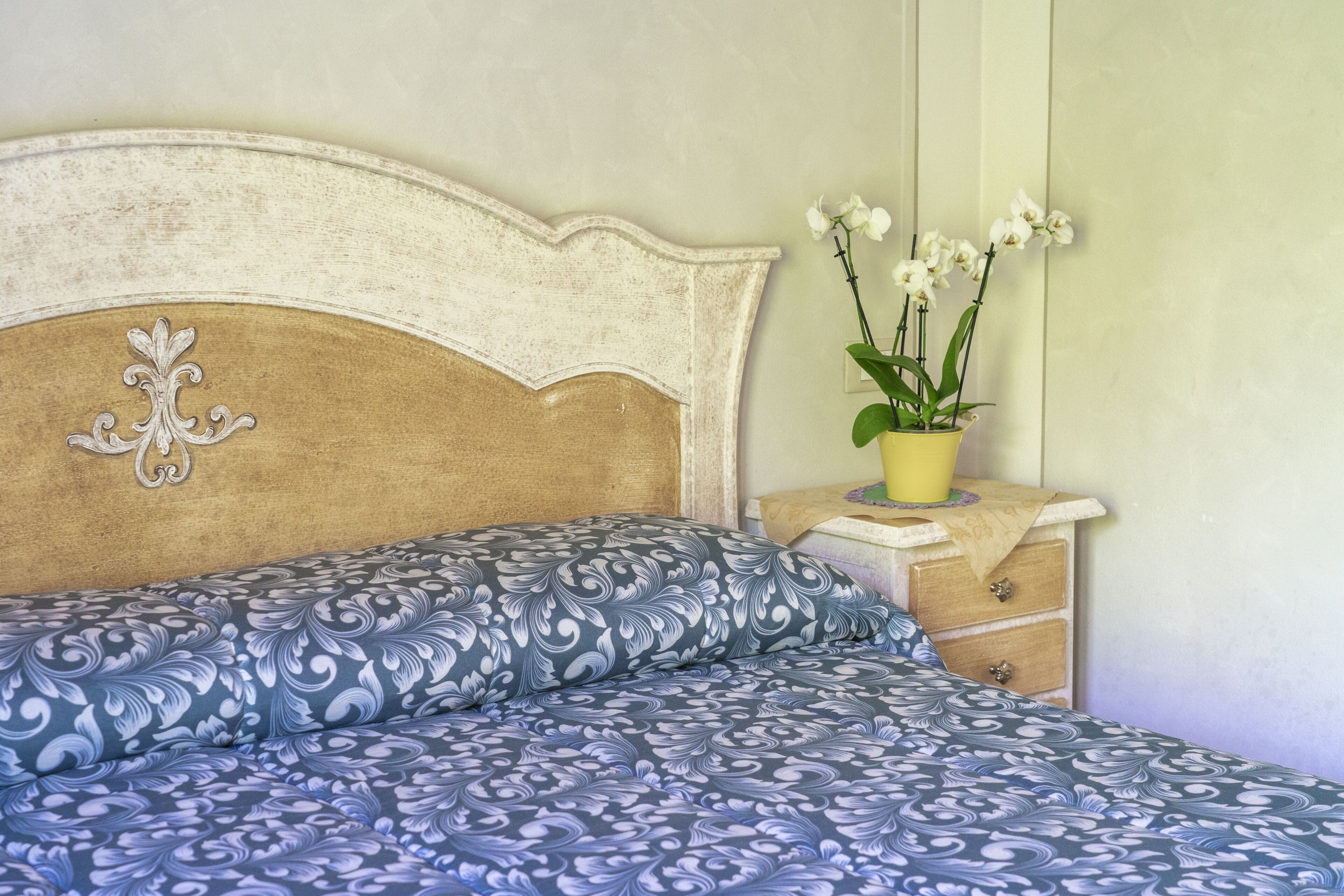 Une chambre à coucher avec un lit, une table de chevet et une orchidée en pot.
