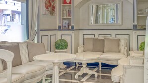 A room with a checkered floor, white sofas, and a round table.