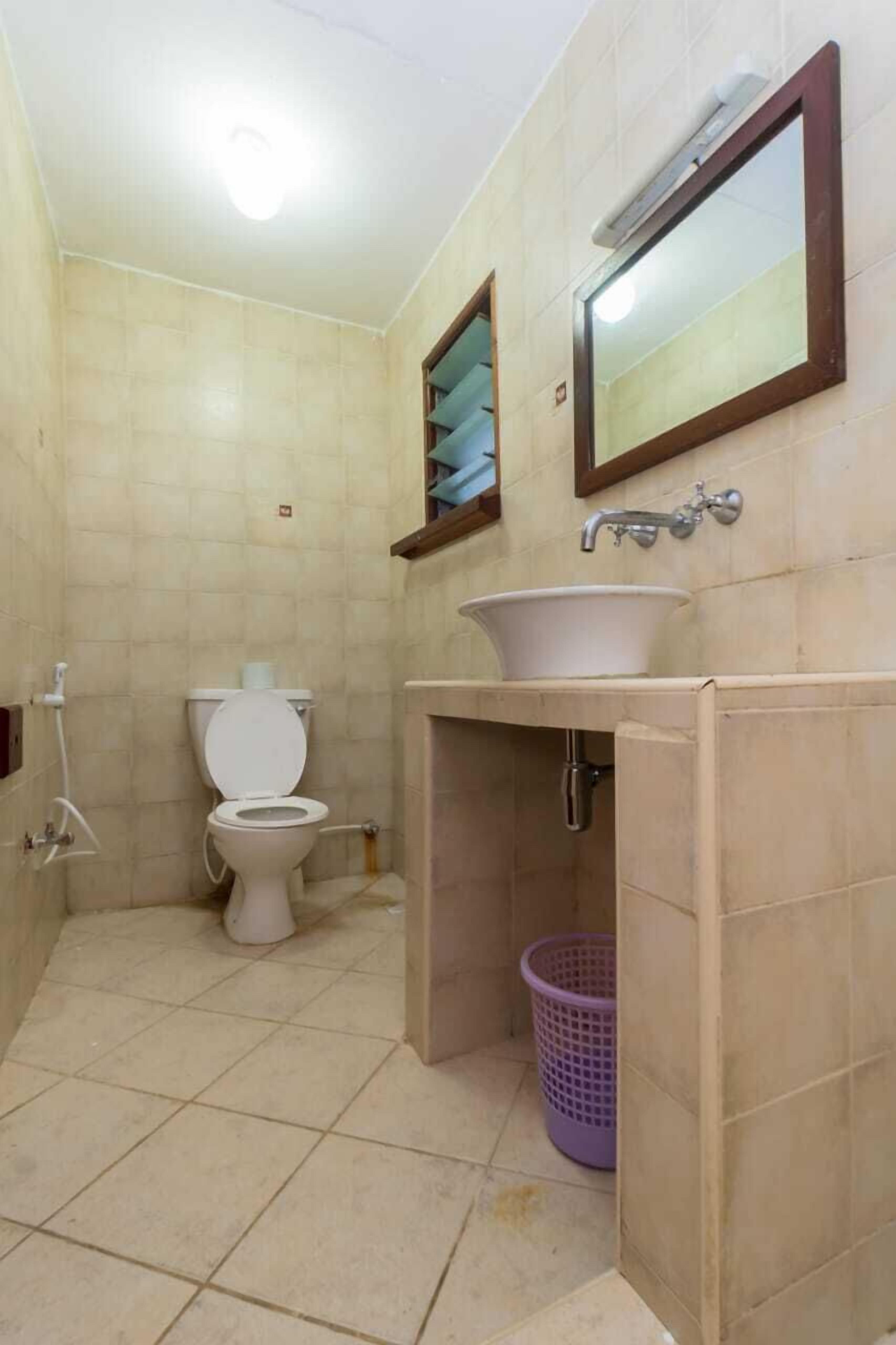A small bathroom with a toilet, sink, and a mirror.