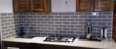 A kitchen with wooden cabinets, a gas stove, a sink, and a tiled backsplash.