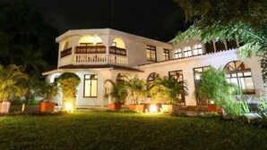 A two-story building with a balcony, surrounded by well-maintained grass and potted plants. - Pontoon Residence & Suites (Mombasa)