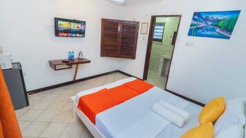 A hotel room with a bed, a desk, a television, and a painting on the wall.