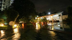 A building with a covered outdoor area, potted plants, and a reflective floor. - Pontoon Residence & Suites (Mombasa)